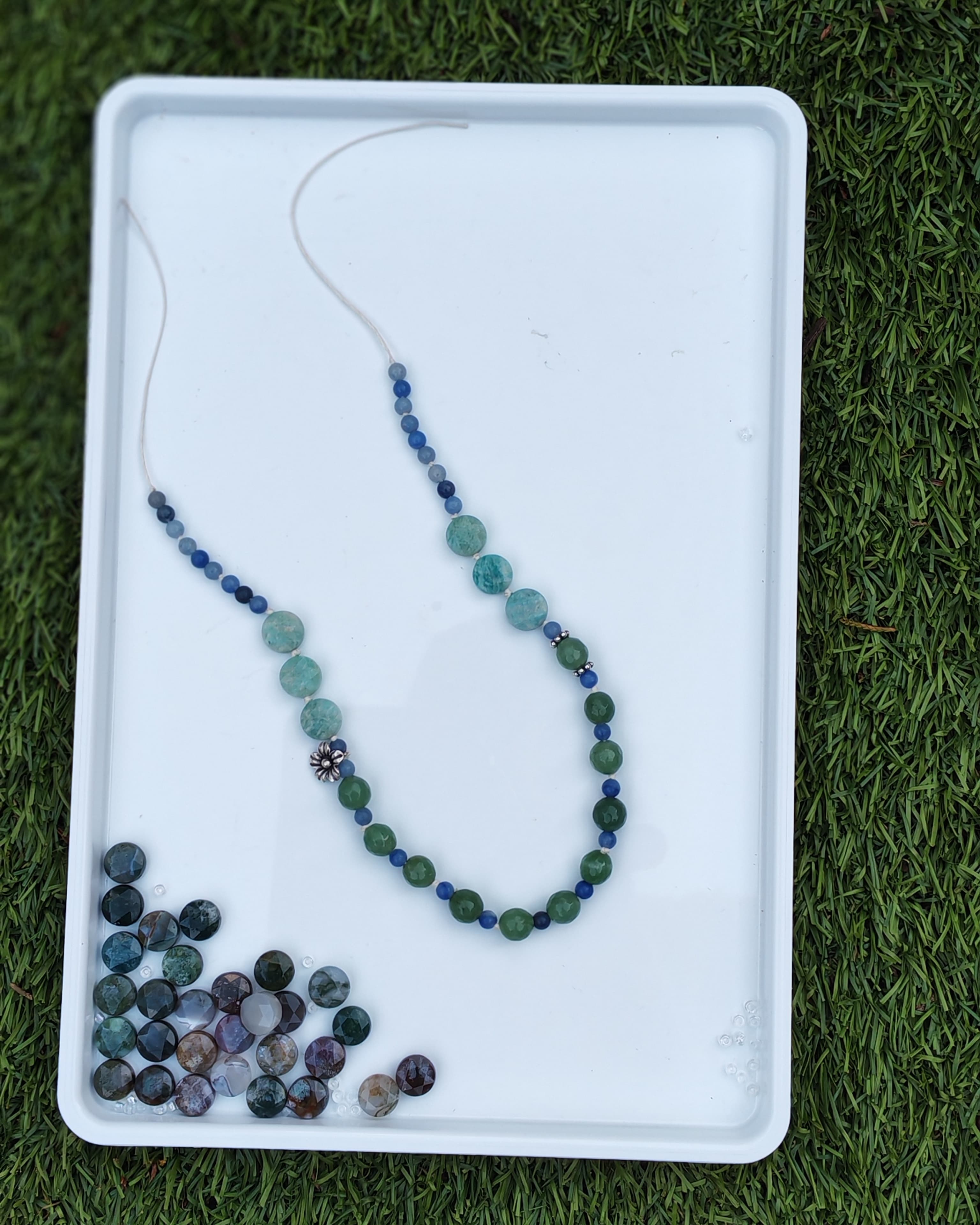 Blue and green necklace on a tray with bead selection